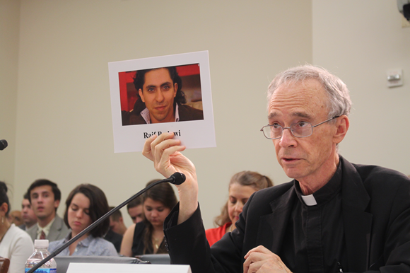 USCIRF Chair Thomas J. Reese, S.J., holds up a photo of Raif Badawi at a July 2016 Tom Lantos Human Rights Commission hearing on Blasphemy Laws